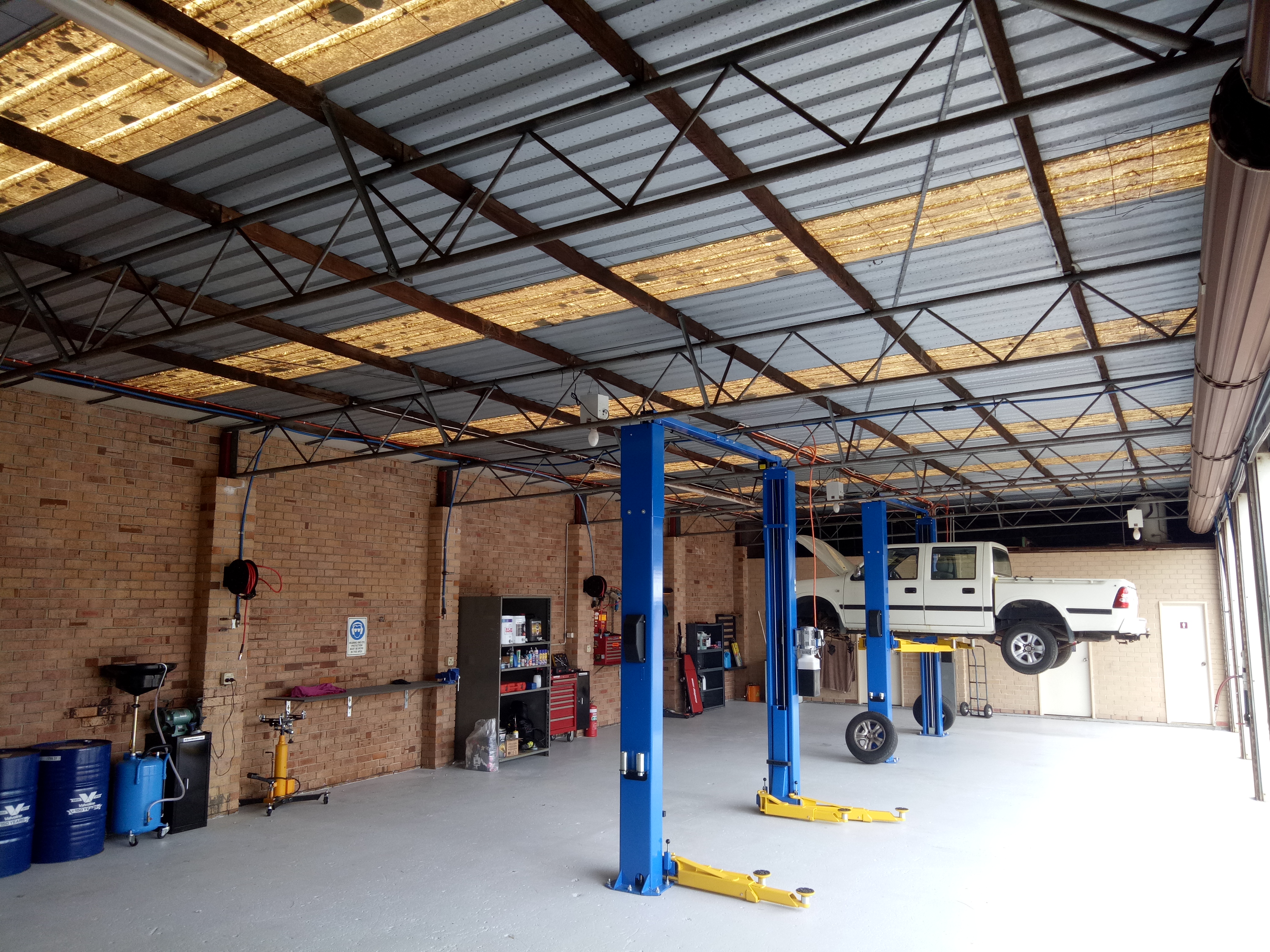 Inside the Albany Mechanical workshop, with two hoists and a ute raised for work